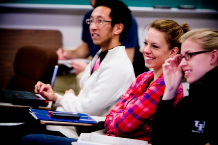 Students sitting and smiling in a classroom during lecture. 