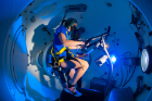 Exercise and Nutrition Sciences (ENS) PhD candidate Courtney Wheelock observes as Jocelyn Stooks, MPH, ENS senior research support specialist, rides a stationary bike in the Center for Research and Education in Special Environments’ hyper/hypobaric chamber.