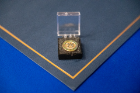 An Alpha Eta honor society pin sits on a table. 