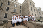 Group photo of the class of 2024 physical therapy students wearing their white coats on the exterior steps of Hayes Hall. 