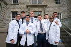 Students celebrate on the steps of Hayes Hall wearing their new white coats. 