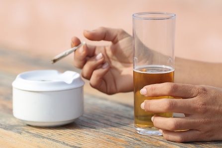 Close up of female hands holding a cigarette and a glass of beer. 