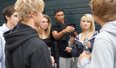 A group of teenagers smoking cigarettes and drinking alcohol. 