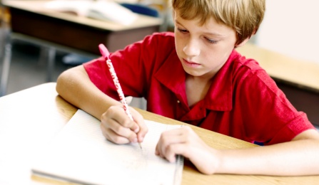Child writing in a notebook at school. 