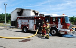 firefighters in front of burnt building. 