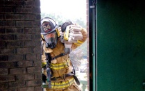 Zoom image: firefighter pulling hose through doorway