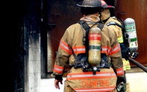 Zoom image: two firefighters outside of burning building