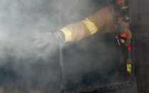 Zoom image: firefighter opening window in smoking building