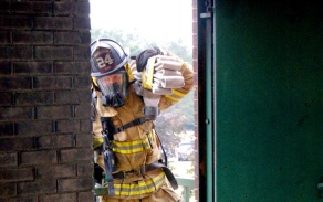 firefighter pulling hose through doorway. 