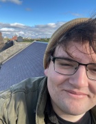 Photo of most of a man's face with glasses on a rooftop. 