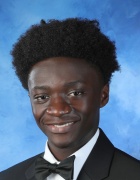 Photo of a dark-skinned young man smiling against a blue background. 