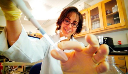 A student placing a specimen in a test tube. 