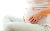 A woman holding her pregnant belly. 