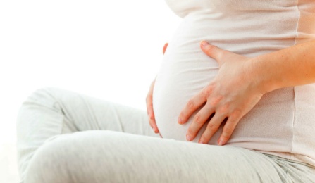 A woman holding her pregnant belly. 