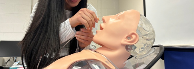 Nutrition student practicing advanced clinical skills: hands-on simulation of feeding tube insertion.