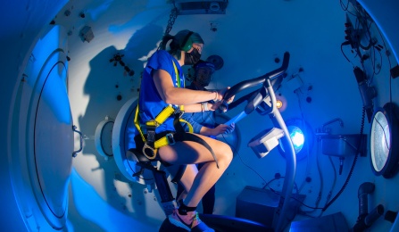 Exercise and Nutrition Sciences (ENS) PhD candidate Courtney Wheelock observes as Jocelyn Stooks, MPH, ENS senior research support specialist, rides a stationary bike in the Center for Research and Education in Special Environments’ hyper/hypobaric chamber. 