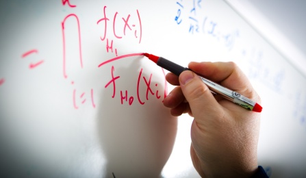 Hand writing equations on a white board. 