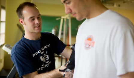 Students interacting in a laboratory testing blood pressure equipment. 