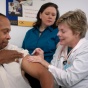 Man receiving immunization shot in his left arm. 
