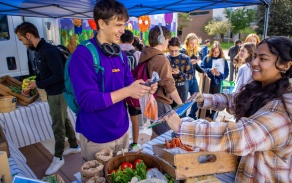 Two attendees at the Veggie Van smiling and interacting in a small crowd. 