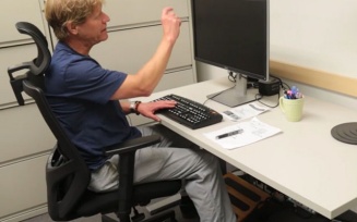 Jim Lenker demonstrates an electric sit-stand desk. 