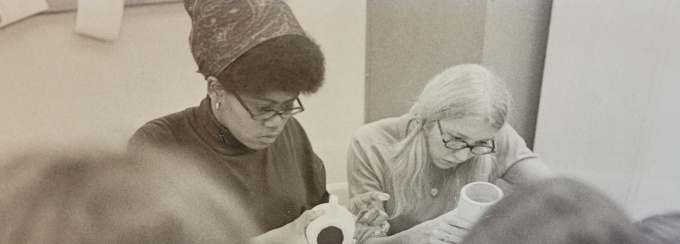 Zoom image: two women work on their clay pots in a 1970s OT lab