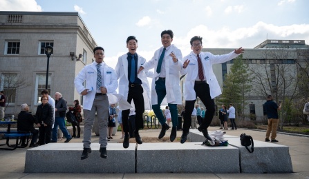 Students wear their white coats on the steps of Farber Hall. 
