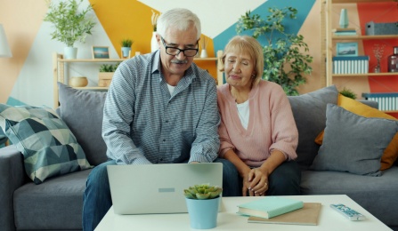 An elderly couple looking at a laptop. 