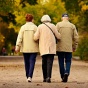 Three people arm in arm walking down a path outside. 