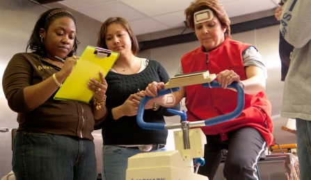 Students conducting research with a subject on a stationary bike. 