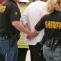 Two sheriffs walking with a man in handcuffs. 