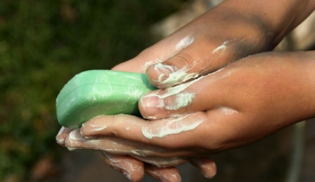 A child cleaning their hands with a bar of soap. 